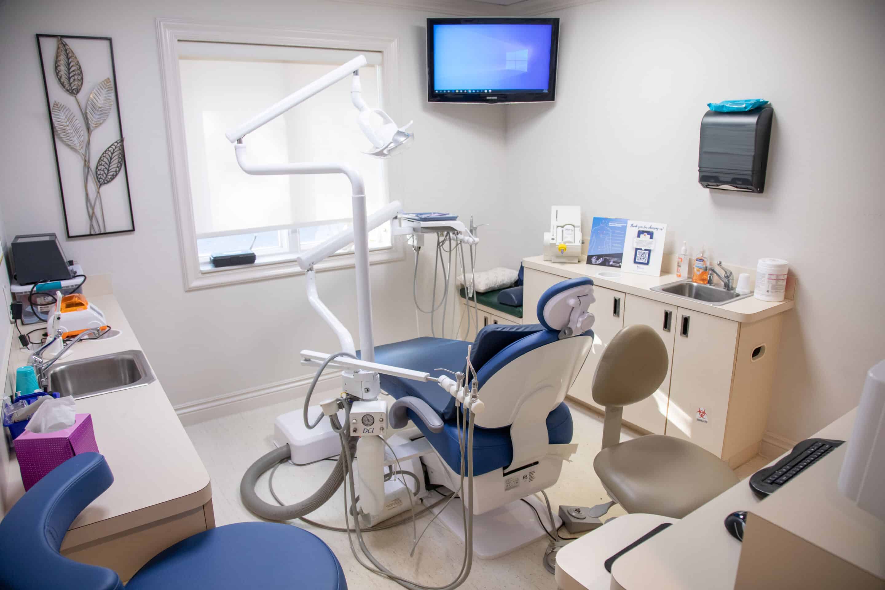 A view inside an exam room, with a computer monitor shown in the top corner and various dental equipment visible.