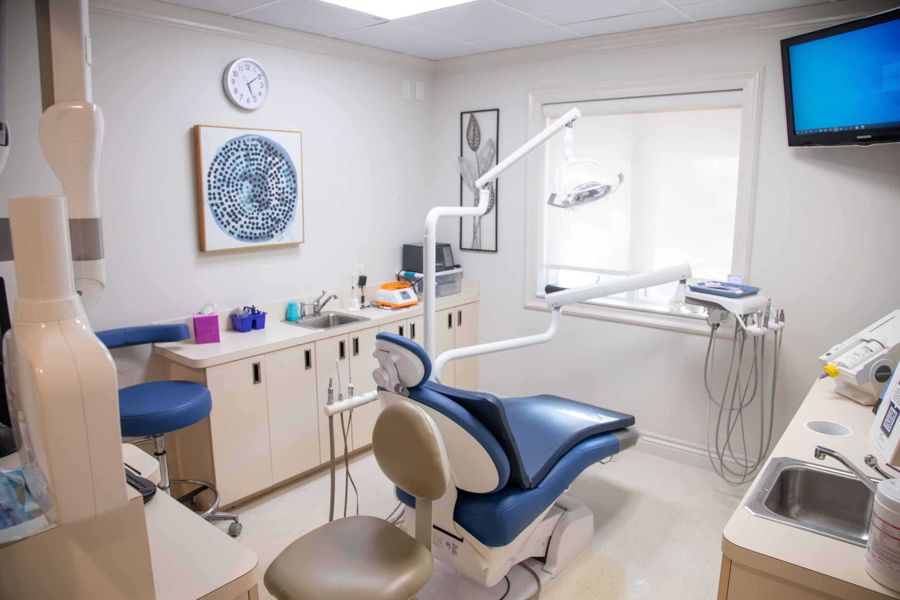 A view inside a dental exam room, with abstract, cool-toned wall art and neatly arranged equipment.